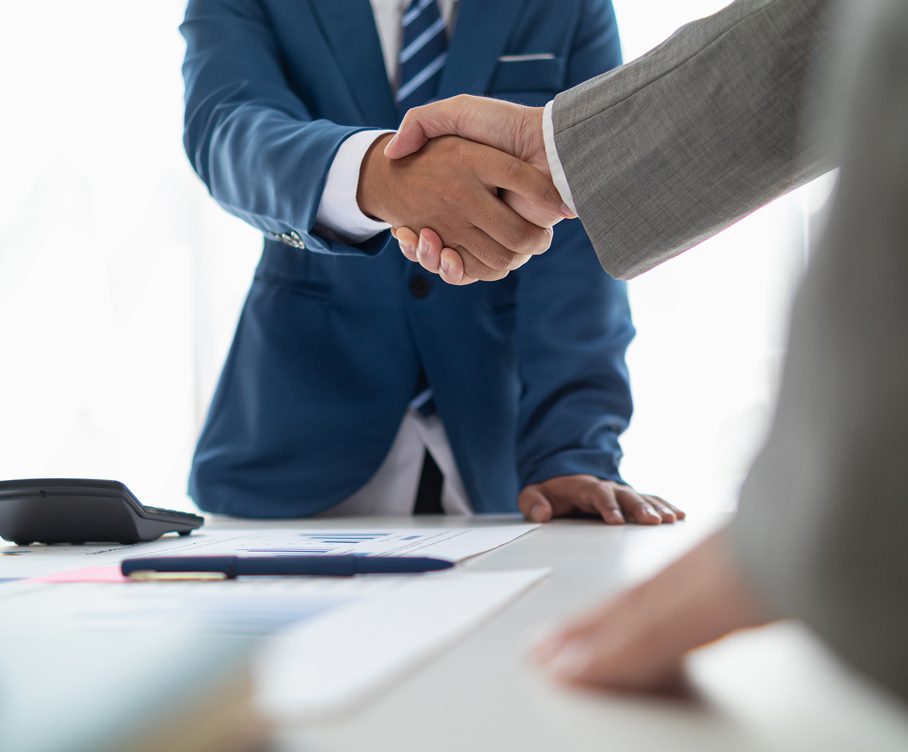 Business handshake over a desk with documents.